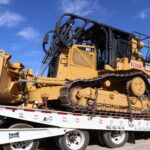 Crawler dozer secured on a lowboy trailer for heavy haul shipping
